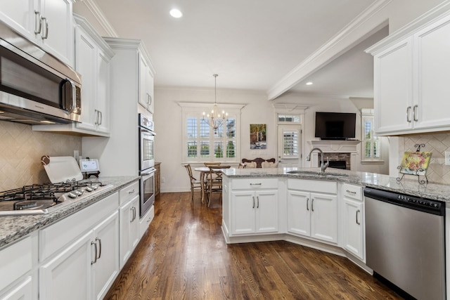 kitchen with appliances with stainless steel finishes, crown molding, sink, pendant lighting, and white cabinetry