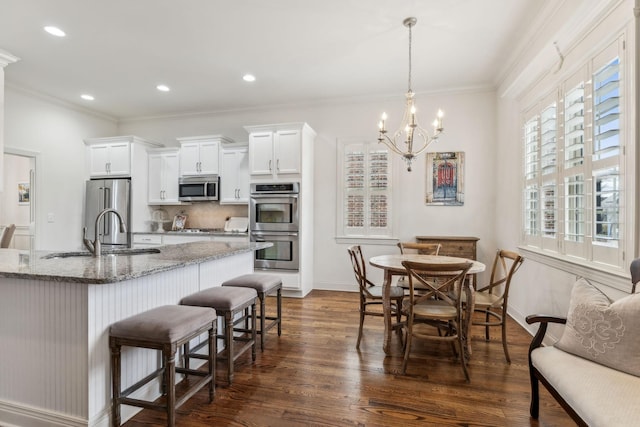 kitchen with pendant lighting, a kitchen breakfast bar, appliances with stainless steel finishes, stone countertops, and dark hardwood / wood-style flooring