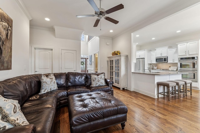 living room with ceiling fan, sink, wood-type flooring, and ornamental molding