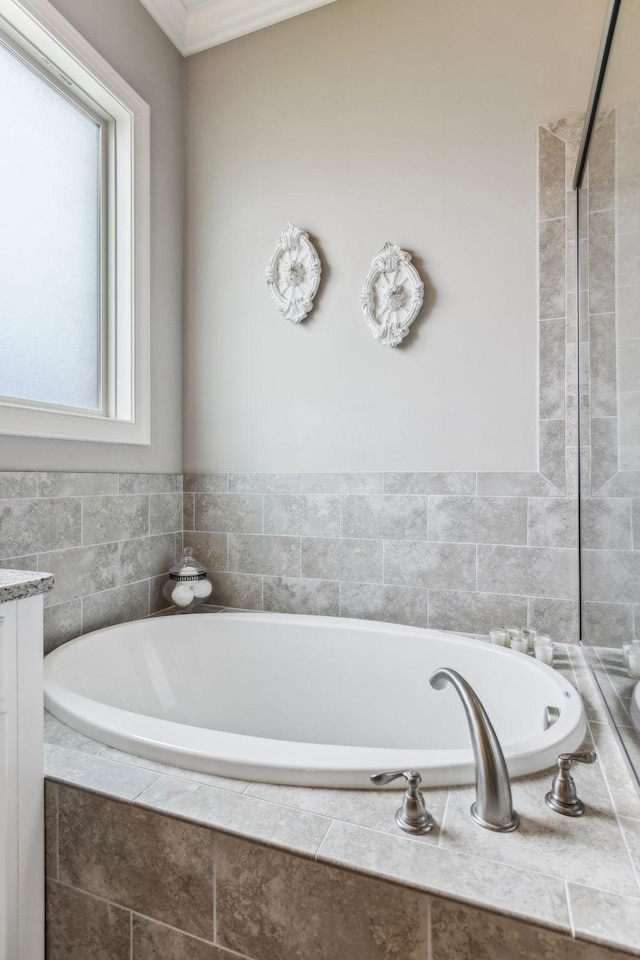 bathroom with vanity, a healthy amount of sunlight, and tiled tub