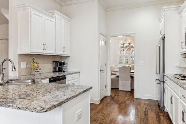 kitchen with light stone countertops, stainless steel appliances, sink, an inviting chandelier, and white cabinets