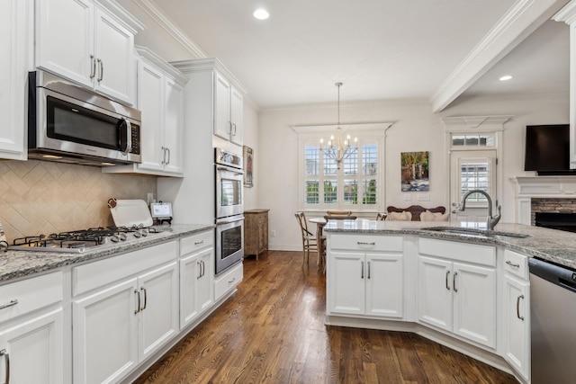 kitchen featuring a stone fireplace, sink, light stone counters, white cabinetry, and stainless steel appliances