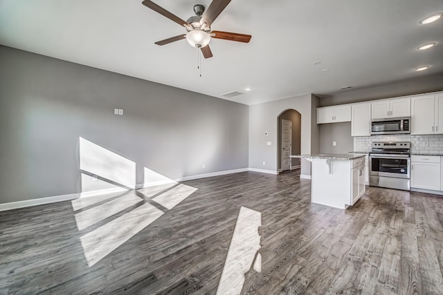 kitchen featuring a breakfast bar, a center island, backsplash, appliances with stainless steel finishes, and white cabinetry