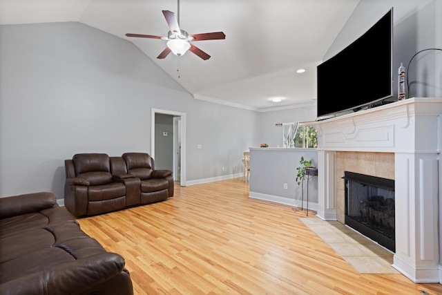 living room with ceiling fan, lofted ceiling, light hardwood / wood-style flooring, and a tiled fireplace