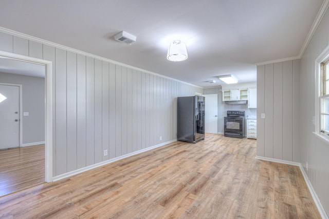 unfurnished living room with ornamental molding, baseboards, and light wood finished floors