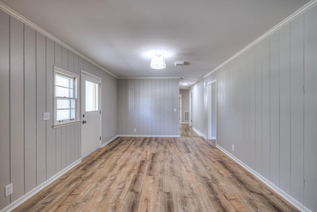 spare room featuring crown molding, baseboards, and wood finished floors