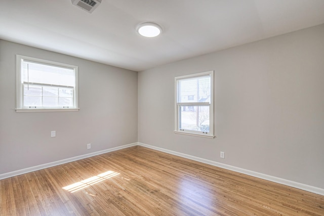 unfurnished room with light wood-style floors, baseboards, visible vents, and a wealth of natural light