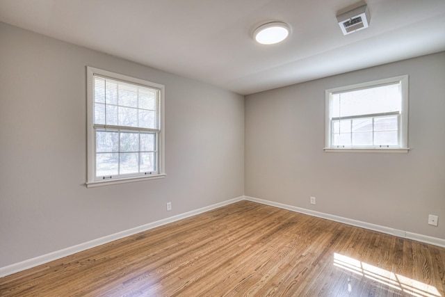 unfurnished room featuring light wood finished floors, visible vents, and baseboards