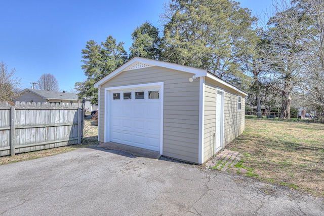 detached garage featuring fence and driveway