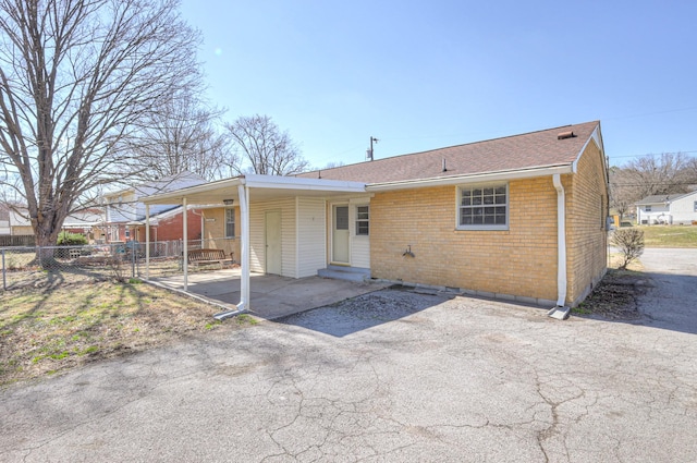 back of property featuring entry steps, roof with shingles, fence, and brick siding