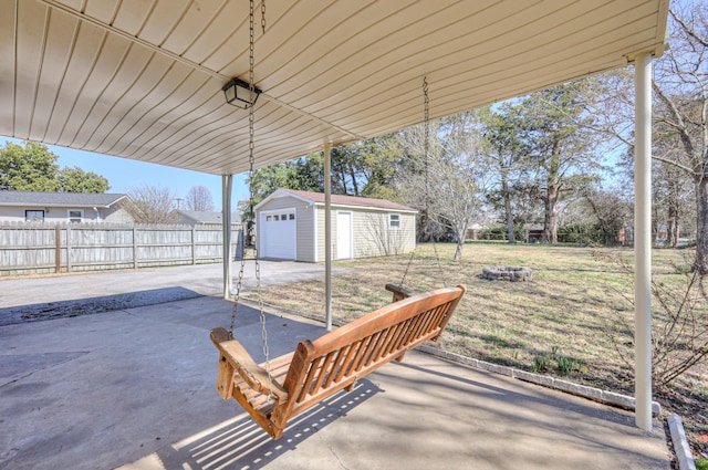 view of patio / terrace with a garage, a fenced backyard, a fire pit, and an outdoor structure