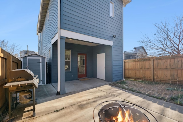 rear view of house with a storage unit, an outdoor fire pit, and a patio