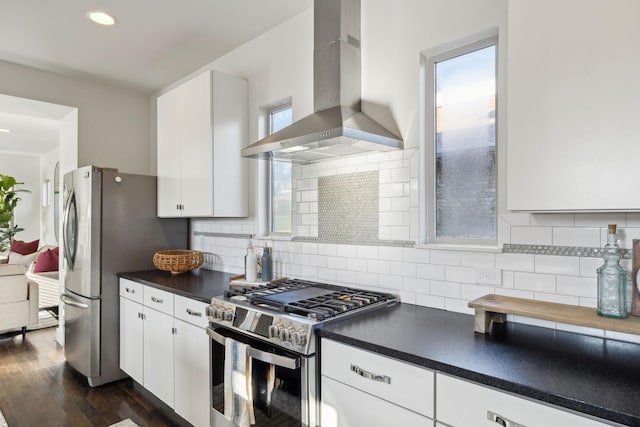 kitchen featuring backsplash, stainless steel appliances, wall chimney range hood, white cabinets, and dark hardwood / wood-style floors