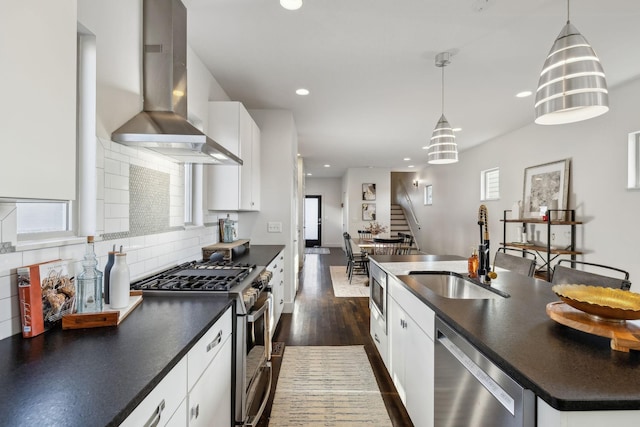 kitchen featuring white cabinetry, pendant lighting, wall chimney range hood, and appliances with stainless steel finishes