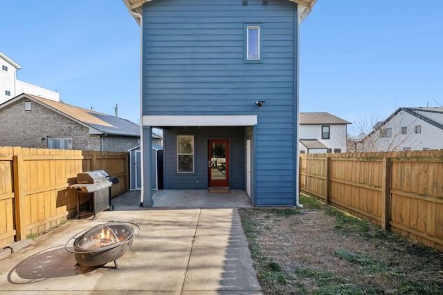 rear view of house featuring a patio, a fire pit, and a storage unit