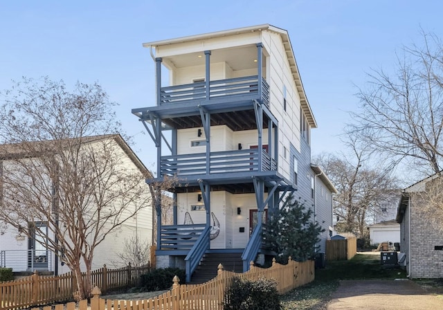 view of front of property featuring a balcony, covered porch, stairs, and fence