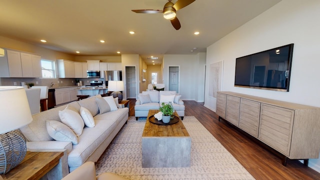 living room with dark wood-type flooring and ceiling fan