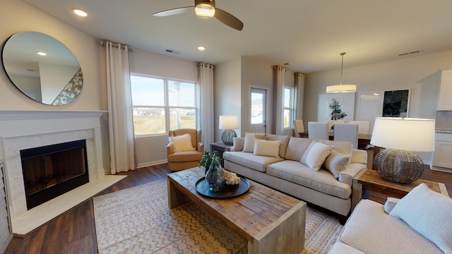 living room featuring a high end fireplace, dark hardwood / wood-style floors, and ceiling fan