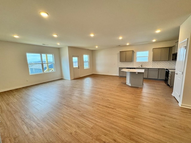 kitchen featuring electric stove, tasteful backsplash, a kitchen island, and light hardwood / wood-style flooring