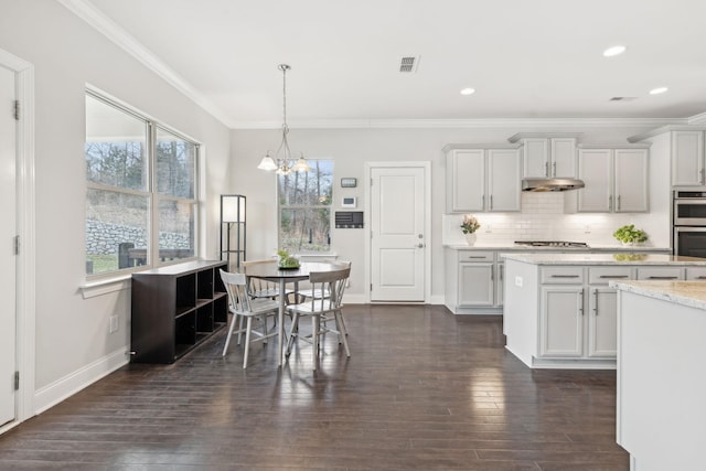 kitchen featuring stainless steel appliances, white cabinetry, hanging light fixtures, and light stone counters