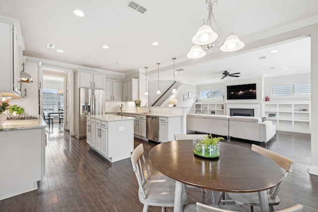 dining area featuring dark hardwood / wood-style flooring, ceiling fan, sink, and ornamental molding