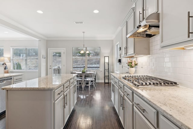 kitchen with stainless steel appliances, crown molding, a chandelier, a center island, and hanging light fixtures