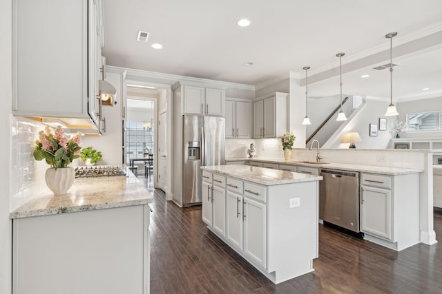 kitchen with tasteful backsplash, stainless steel appliances, sink, a kitchen island, and hanging light fixtures