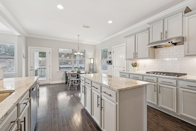 kitchen featuring light stone countertops, decorative light fixtures, stainless steel appliances, and ornamental molding