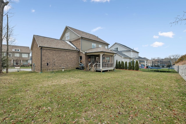 rear view of house with a lawn, a sunroom, and a trampoline