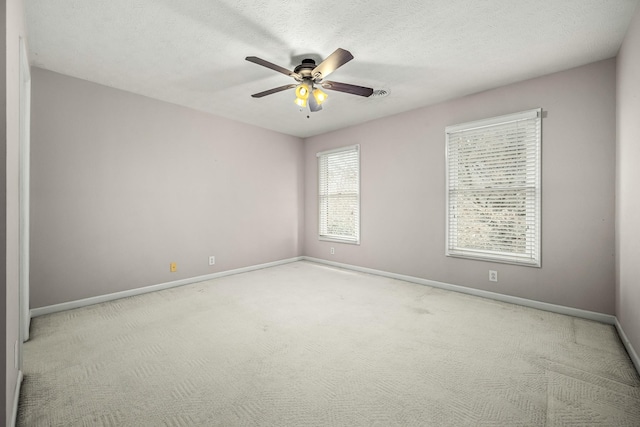 empty room with a textured ceiling, light colored carpet, and ceiling fan