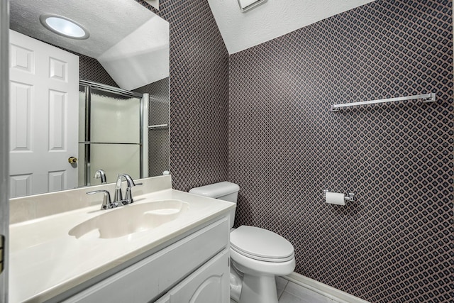 bathroom with lofted ceiling, a textured ceiling, toilet, vanity, and a shower with shower door