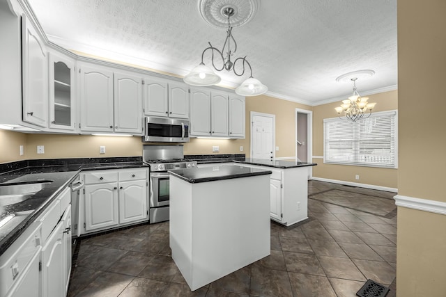 kitchen with white cabinetry, a kitchen island, hanging light fixtures, and appliances with stainless steel finishes