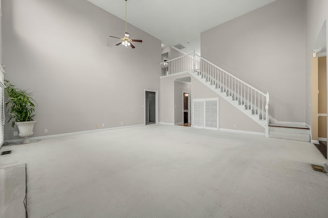 unfurnished living room featuring carpet, ceiling fan, and a towering ceiling