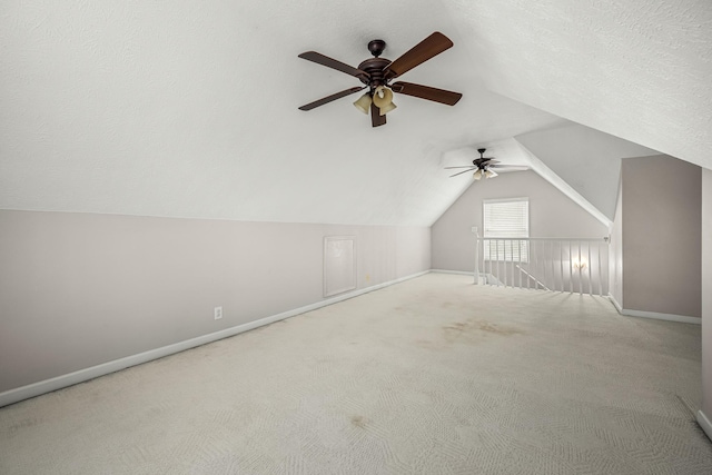 additional living space featuring vaulted ceiling, ceiling fan, light colored carpet, and a textured ceiling