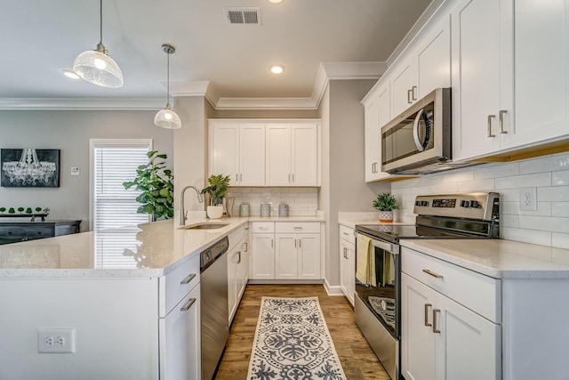 kitchen with white cabinets, appliances with stainless steel finishes, decorative light fixtures, and sink