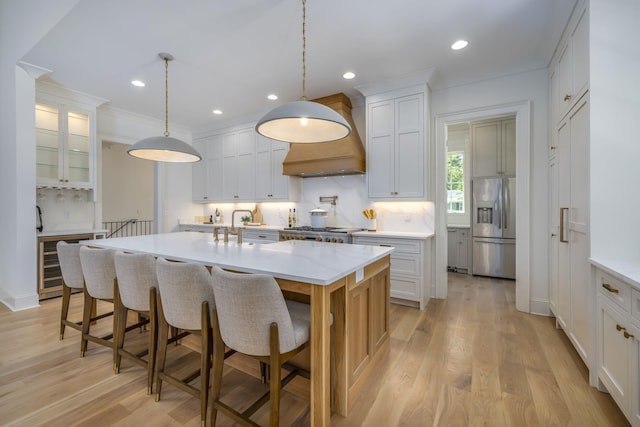 kitchen with backsplash, white cabinets, stainless steel refrigerator with ice dispenser, and an island with sink