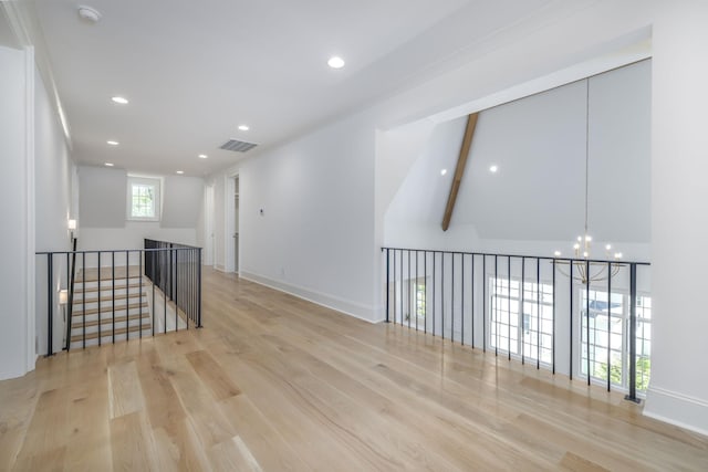 spare room featuring vaulted ceiling with beams, a wealth of natural light, light hardwood / wood-style floors, and a notable chandelier