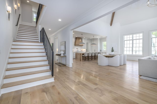 staircase with beamed ceiling, hardwood / wood-style floors, high vaulted ceiling, and ornamental molding