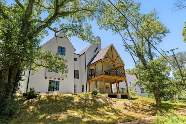 rear view of property with a balcony and a yard