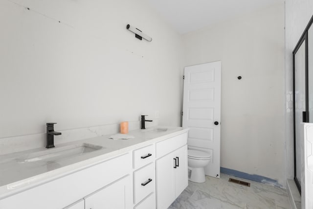 full bathroom with double vanity, toilet, marble finish floor, and a sink