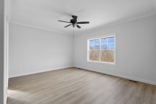 empty room featuring crown molding, wood finished floors, visible vents, and baseboards