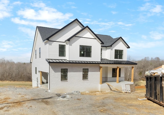 exterior space featuring a standing seam roof, metal roof, brick siding, and a shingled roof