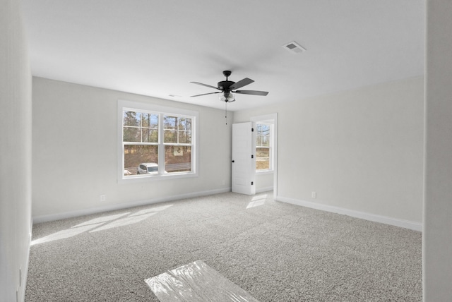 spare room with a ceiling fan, visible vents, carpet, and baseboards