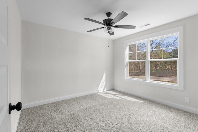 carpeted spare room featuring baseboards, visible vents, and ceiling fan