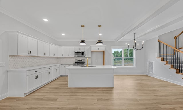 983 Palmyra Rd, Clarksville, TN 37040 - kitchen with stainless steel appliances, white cabinets, a chandelier, crown molding, and light wood finished floors