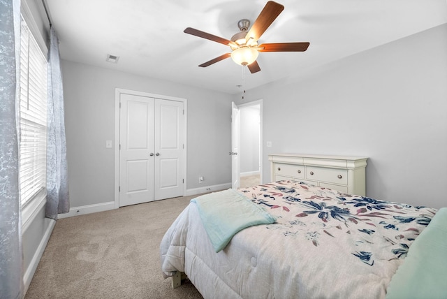 carpeted bedroom with multiple windows, a closet, and ceiling fan