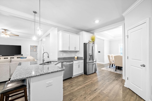 kitchen featuring white cabinets, appliances with stainless steel finishes, hanging light fixtures, and a kitchen breakfast bar