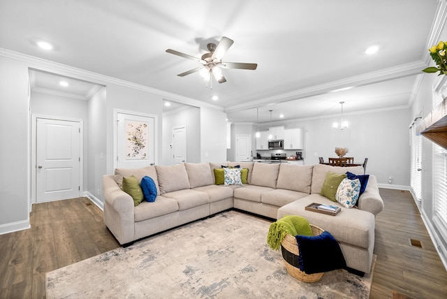 living room featuring dark hardwood / wood-style floors, ceiling fan with notable chandelier, and ornamental molding