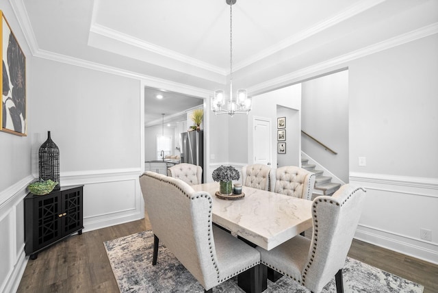 dining area with dark hardwood / wood-style flooring, a raised ceiling, crown molding, and a notable chandelier