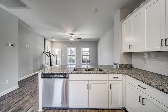 kitchen with kitchen peninsula, stainless steel dishwasher, sink, stone countertops, and white cabinets